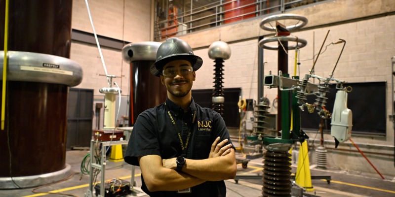 man smiling in a hard hat in a manufacturing room