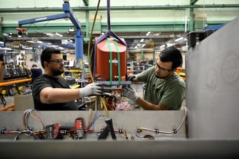Employees collaborating on the assembly of industrial equipment in a manufacturing facility.